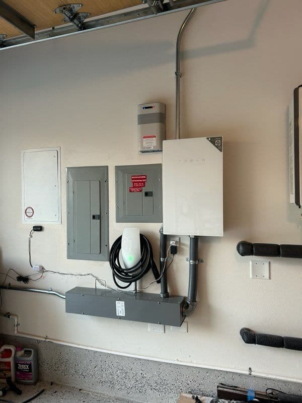 Tesla Powerwall and electric panel installation in a garage wall.