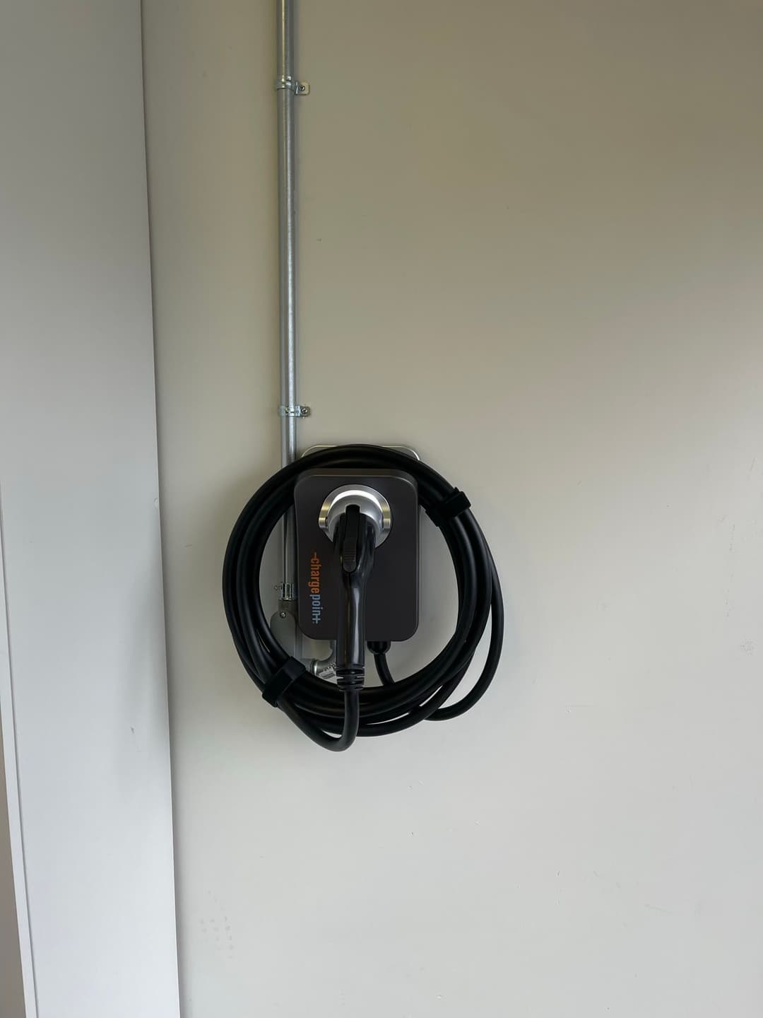 Electric vehicle charging station mounted on a wall with coiled charging cable.