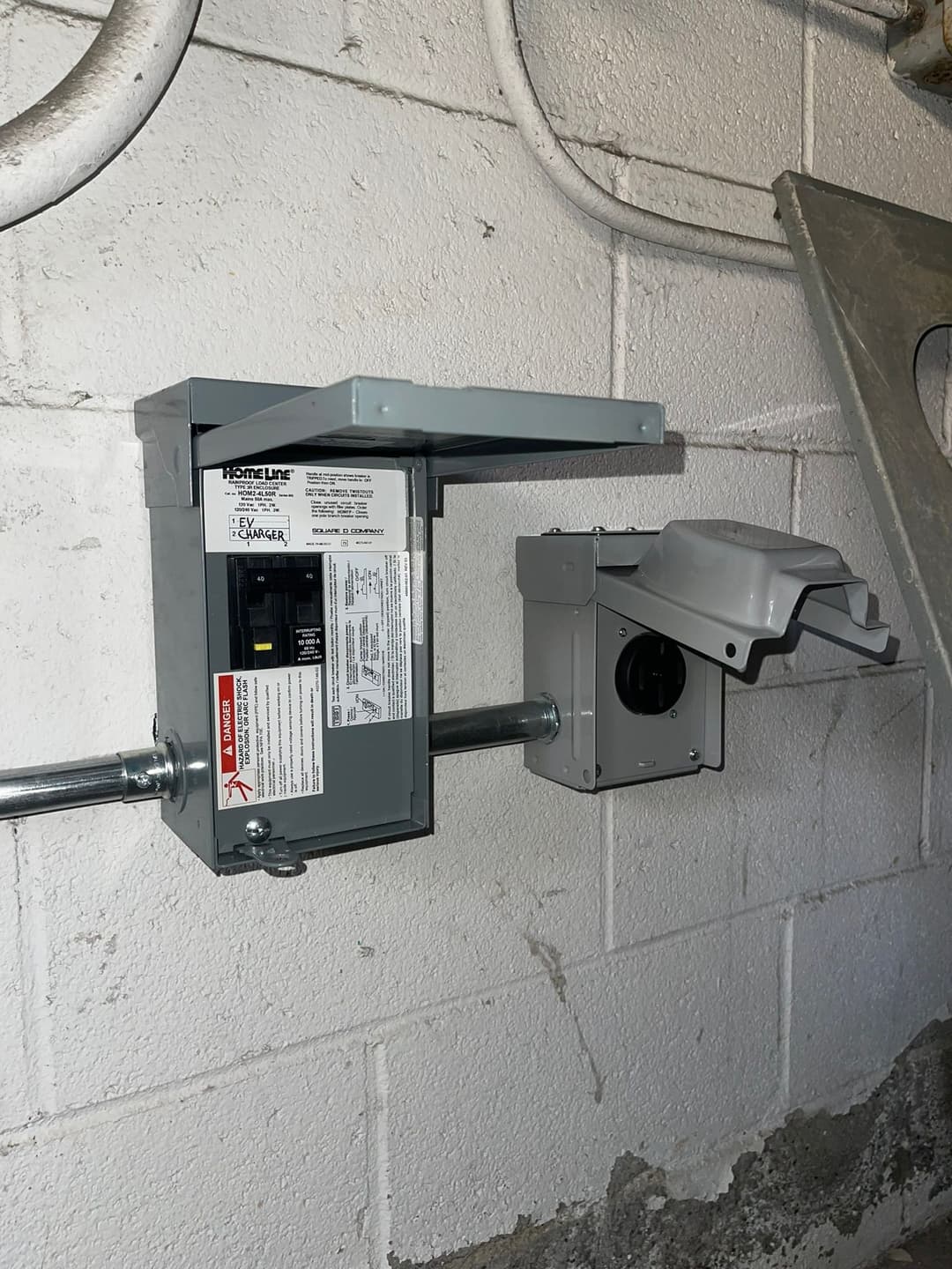 Electrical panel installation with circuit breaker and outlet box in a basement setting.