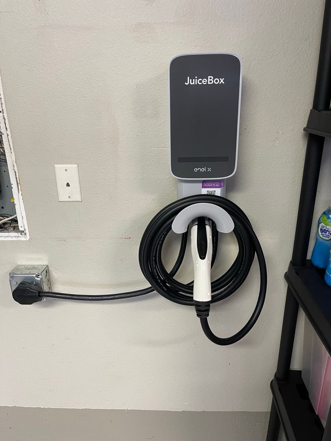 JuiceBox electric vehicle charger mounted on a garage wall with a charging cable.