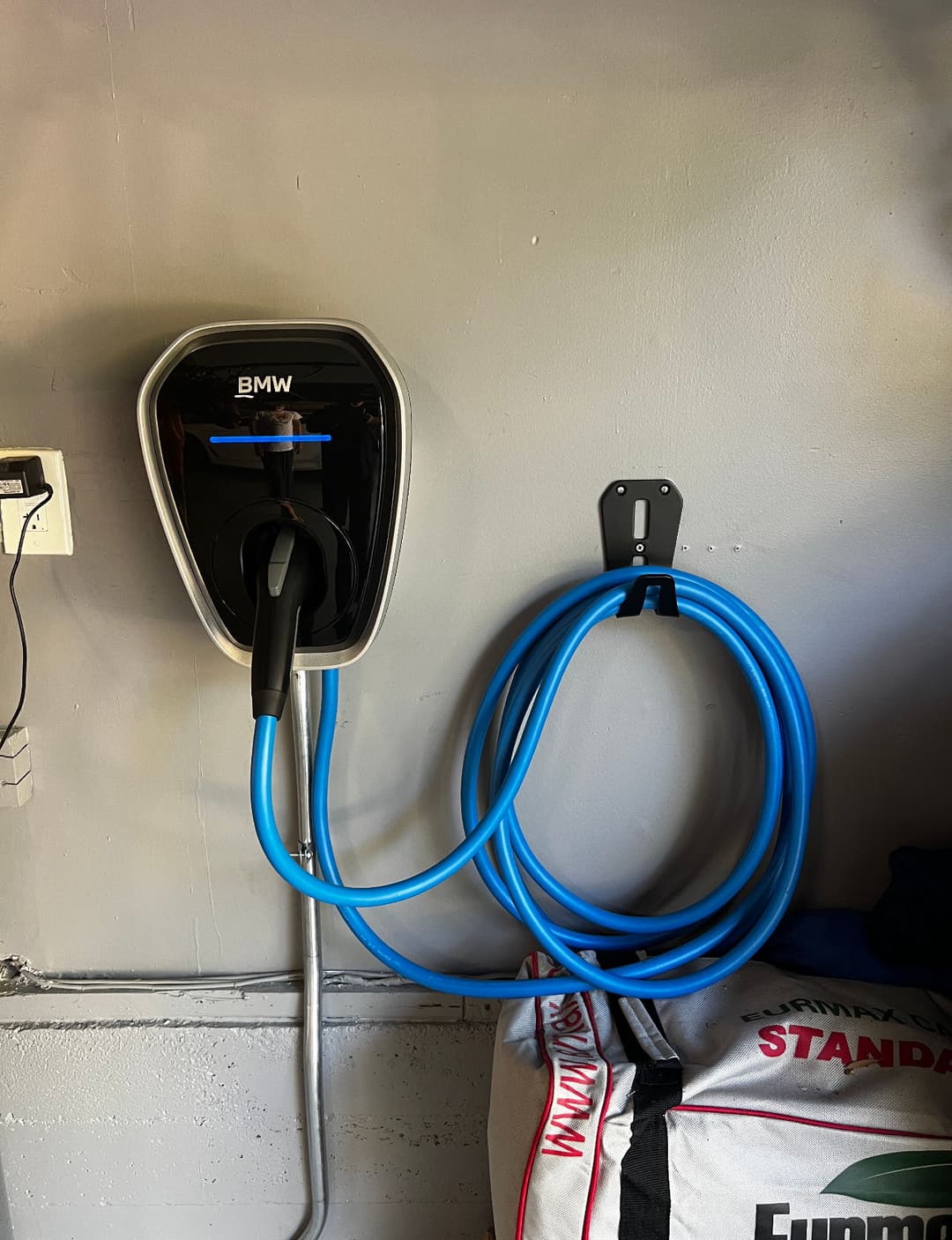 BMW electric vehicle charger mounted on a wall with connected charging cable.