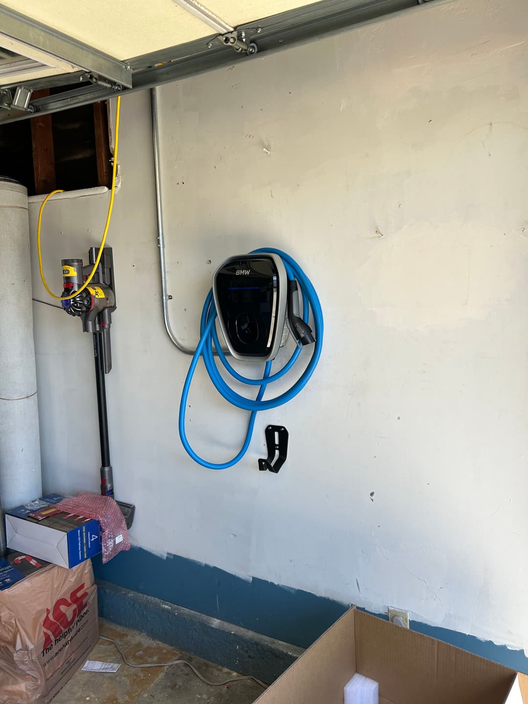 Electric vehicle charger mounted on a garage wall with blue charging cable neatly coiled.