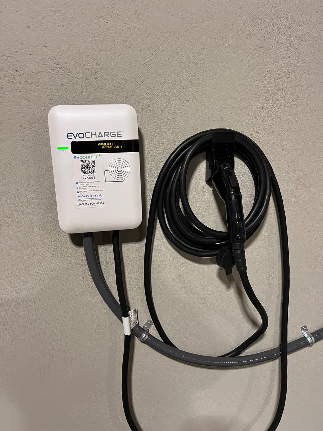 EV charging station mounted on a wall with a charging cable attached.