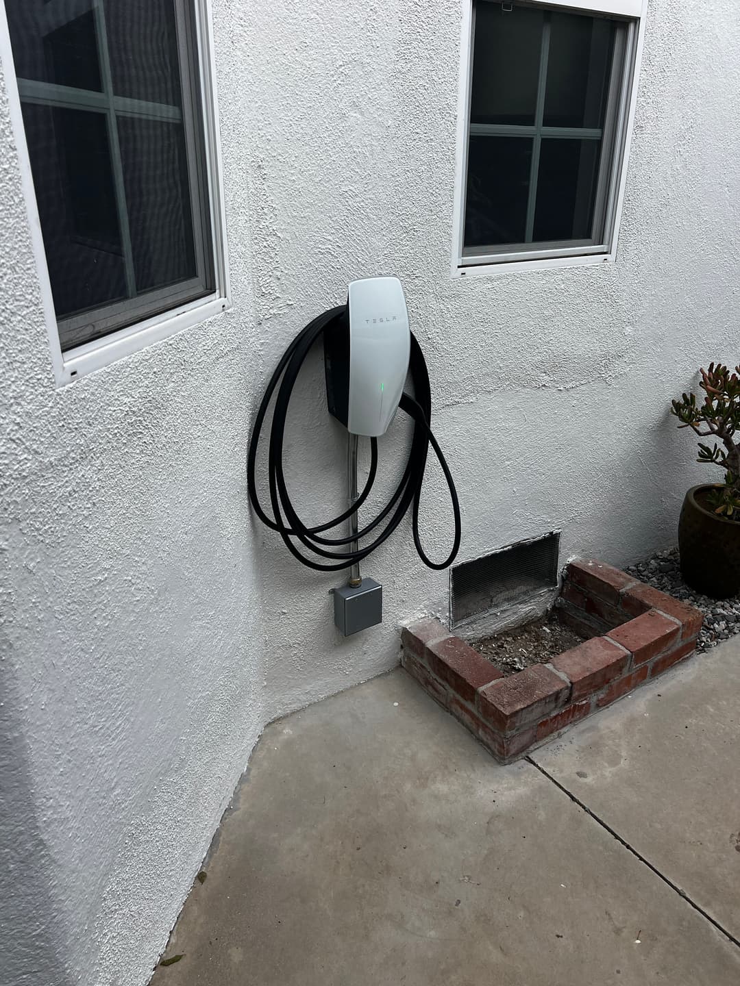 Electric vehicle charger mounted on a wall with cables neatly coiled nearby.