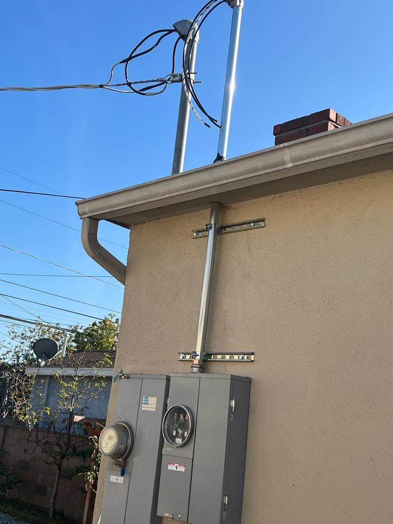 Electric meter and service panel on the side of a house under a clear blue sky.