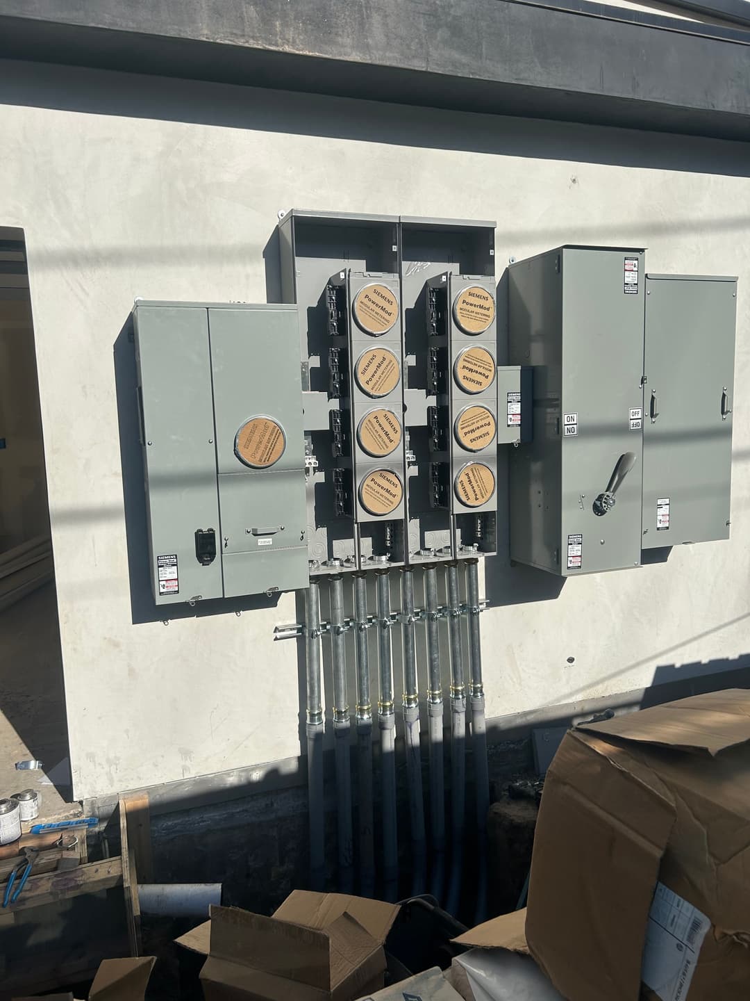 Electrical panel installation with multiple circuit breakers and conduits on a wall.