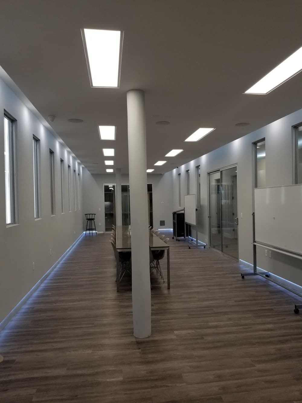 Modern office interior with long conference table, glass walls, and bright lighting.