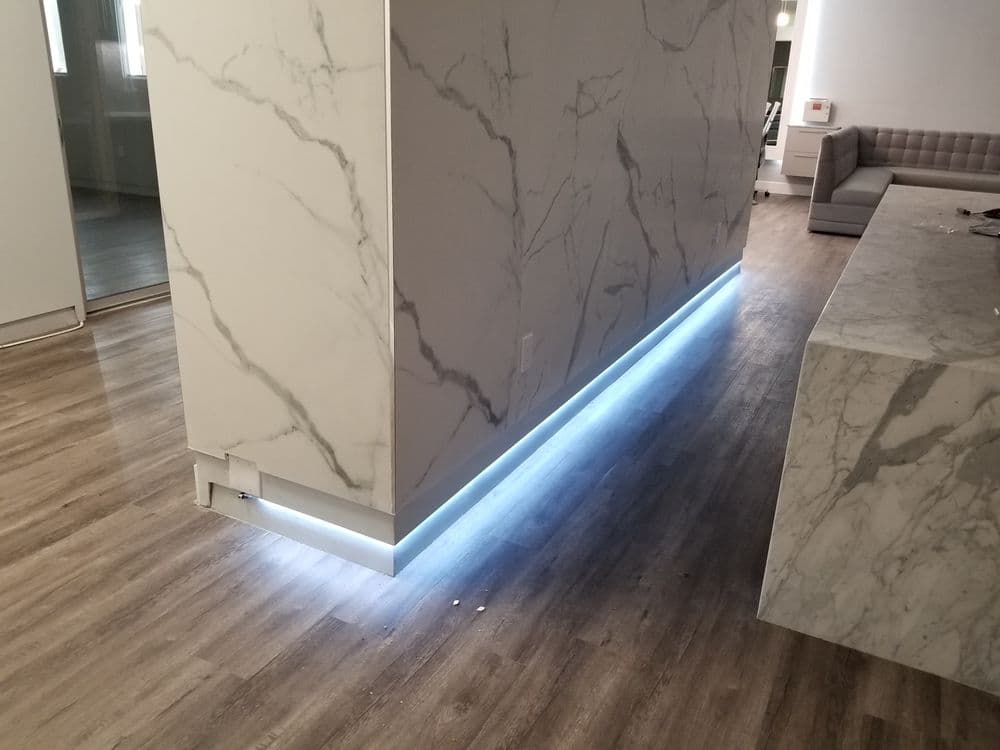 Modern interior with marble wall and LED lighting along the base, wooden flooring.