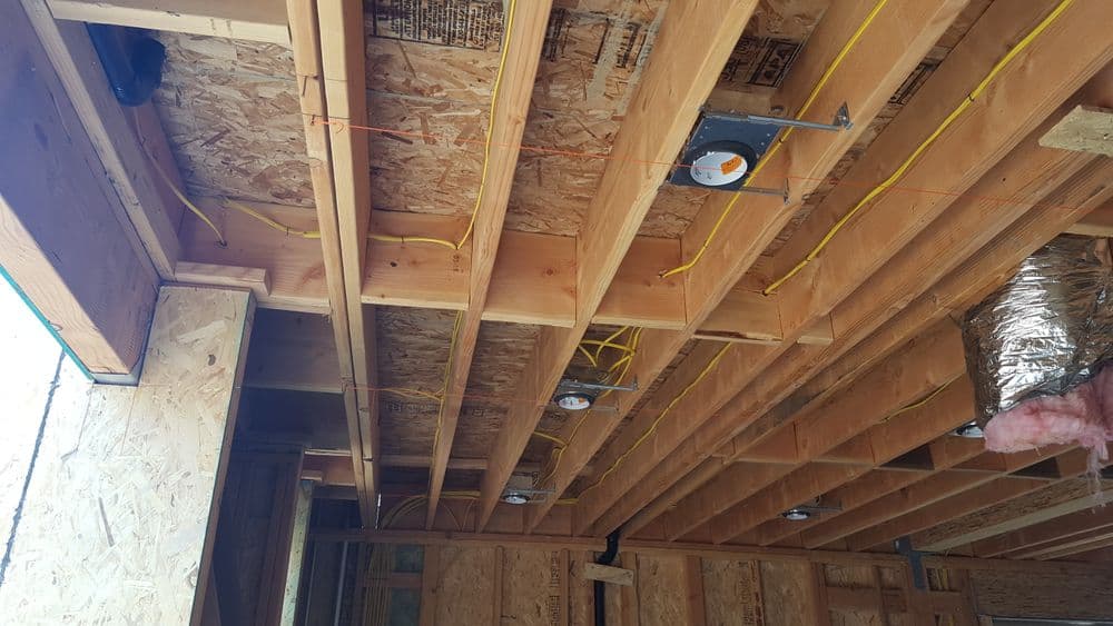 Interior construction showing wooden beams and electrical wiring in a new building.