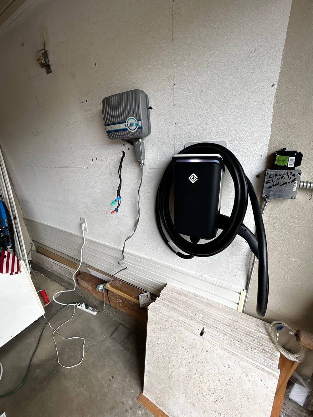 Electric vehicle charging station mounted on a garage wall with charging cable.